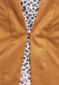 Brun imitationmockasinh sportsjacka med sjalkrage, med ett blommönsterfoder i vitt, marinblått och rött. Mjuk textur, skräddarsydd passform.