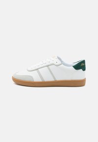 Sneaker bianche con accenti grigi e un tallone verde. Presentano una suola in gomma e un design con lacci. Materiali in pelle liscia e suede.
