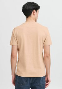 Light beige short-sleeve T-shirt made of soft cotton with a crew neck, featuring a simple design and relaxed fit. Back view shown.