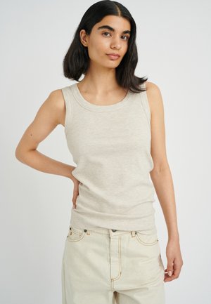 Hellbeige gerippter Tank-Top mit Rundhalsausschnitt und breiten Schulterträgern, kombiniert mit creamfarbenen hochtaillierten Jeans.