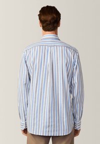 Camicia a maniche lunghe a righe bianche e blu con plissage sul retro. Presenta un colletto classico ed è realizzata in tessuto testurizzato.