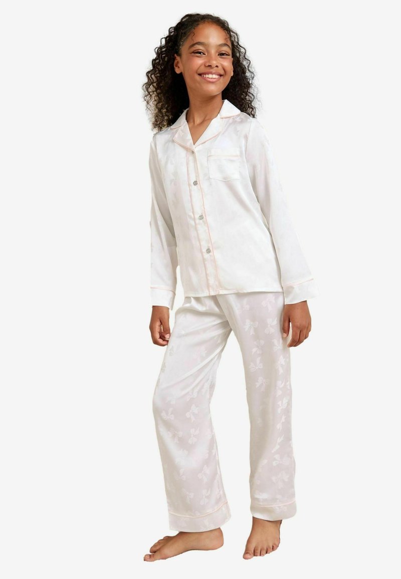 Set di pigiama bianco con una maglia con bottoni, tasca e maniche lunghe. I pantaloni presentano un delicato motivo a farfalle e una leggera lucentezza. Accentuati da dettagli in rosa.