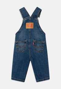 Tmavě modré džínové lacláče s nastavitelnými ramínky, přední kapsou a dvěma zadními kapsami s koženou značkou na zadní straně.