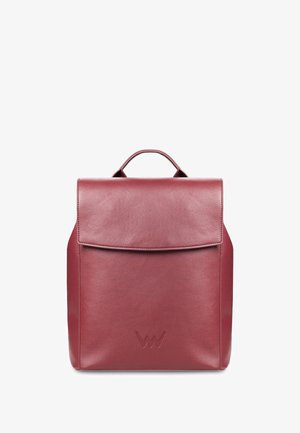 Dunkelroter Leder-Rucksack mit Klappe, oberem Griff und Seitentasche. Getragen mit einem grauen, strukturierten Mantel und einer blauen Strickmütze.