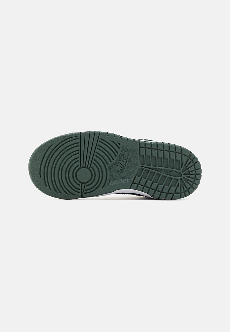 Suela de zapatilla Nike, material de goma, color verde, texturizada con patrones circulares y lineales, incluye detalle del logo de la marca.