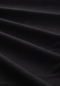 Tissu en coton noir, texture lisse, avec un léger éclat. Drapé en douces plis, mettant en valeur la flexibilité et la douceur.