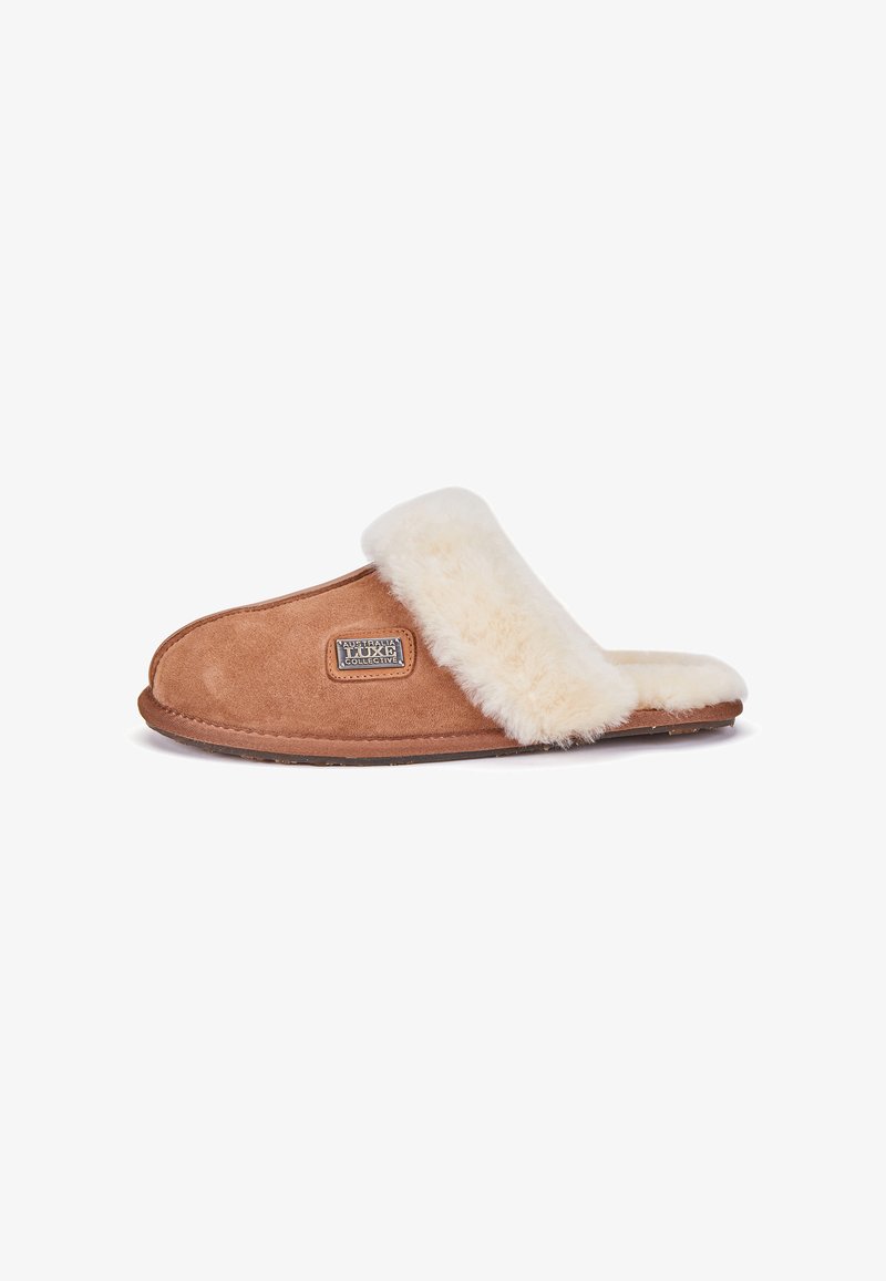 Mocassin en suède marron avec une sangle et une doublure en fourrure synthétique couleur crème, bout rond, semelle plate et logo sur le côté.