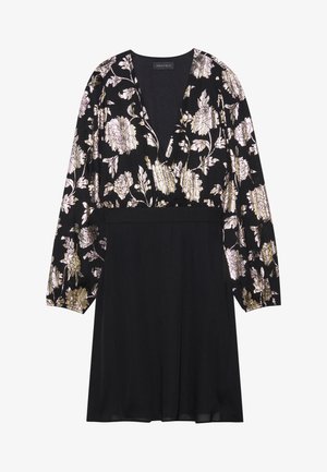 Vestido negro con mangas largas, con un patrón floral en dorado y plateado en la parte superior y una falda negra sólida texturizada. Diseño de escote en V.