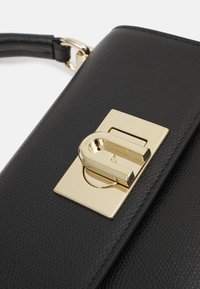 Bolsa de mão em couro preto com acabamento texturizado, apresentando um fecho de metal dourado retangular e uma alça fina preta.