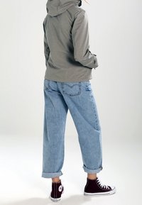 Veste à capuche grise, jean ample bleu clair, revers de manches retroussés, et baskets montantes bordeaux. Texture lisse, style décontracté, sans motifs visibles.