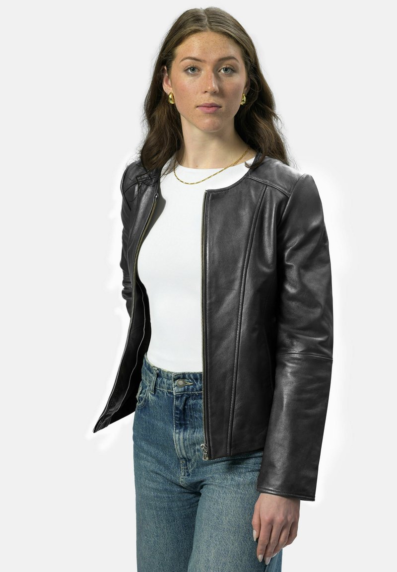 Schwarze Lederjacke mit einem Reißverschluss auf der Vorderseite, rundem Ausschnitt und glatter Textur, kombiniert mit einem weißen Top und hoch waisted blauen Jeans.