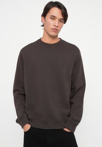 Sudadera marrón hecha de mezcla de algodón, con cuello redondo, mangas largas, puños acanalados y un pequeño logo en el pecho.