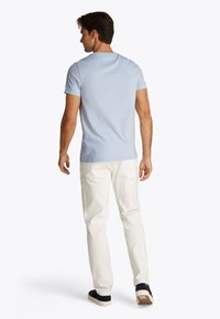 Light blue cotton t-shirt with short sleeves, round neckline, paired with white denim jeans and navy shoes, showcasing a casual fit.