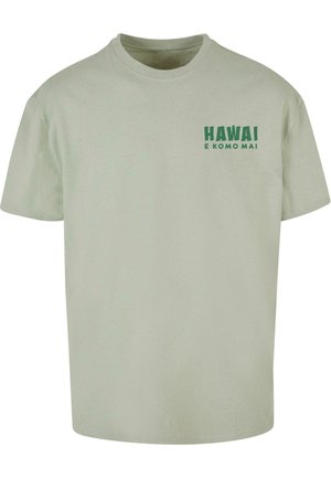 Tricou din bumbac verde deschis, cu mâneci scurte, guler rotund și text imprimat "HAWAI E KOMO MAI" în verde închis pe pieptul stâng.