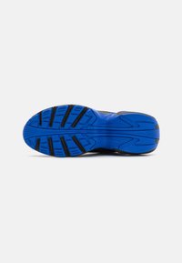 Suola di scarpa sportiva blu con gomma texturizzata, caratterizzata da scanalature profonde e punti di flessibilità per trazione e stabilità. Tacco e punte rinforzati.