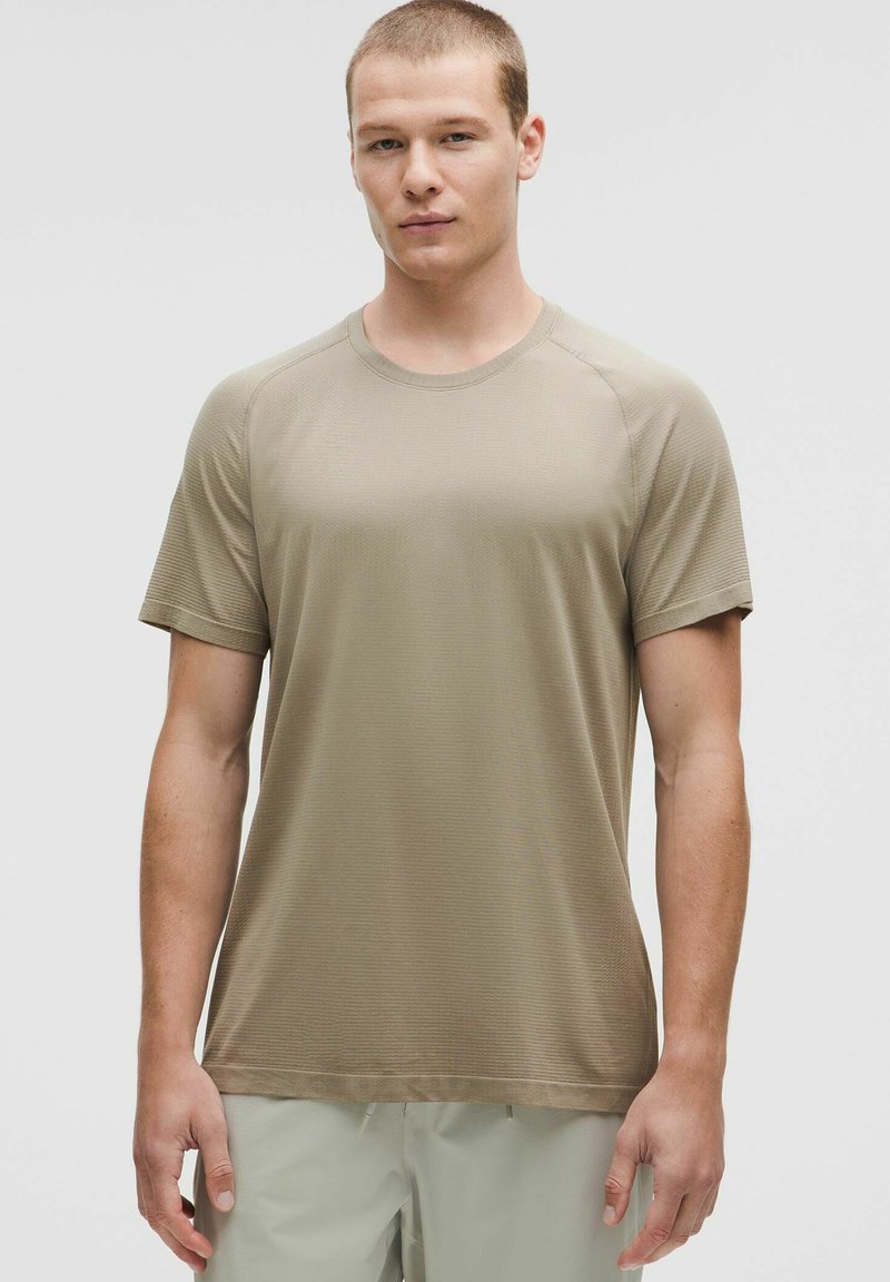 Kurzärmliges, Rundhals-T-Shirt in einem muted beige Farbton, aus strukturiertem Stoff mit subtiler Rippung, das eine enganliegende Silhouette bietet.