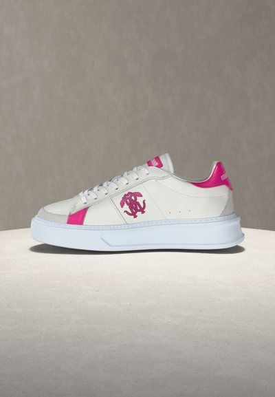 Λευκό παπούτσι τύπου σνίκερ χαμηλού ύψους με ροζ λεπτομέρειες, λογότυπο στο πλάι, παχιά λευκή σόλα και κορδόνια, εμφανίζεται σε ουδέτερο φόντο.