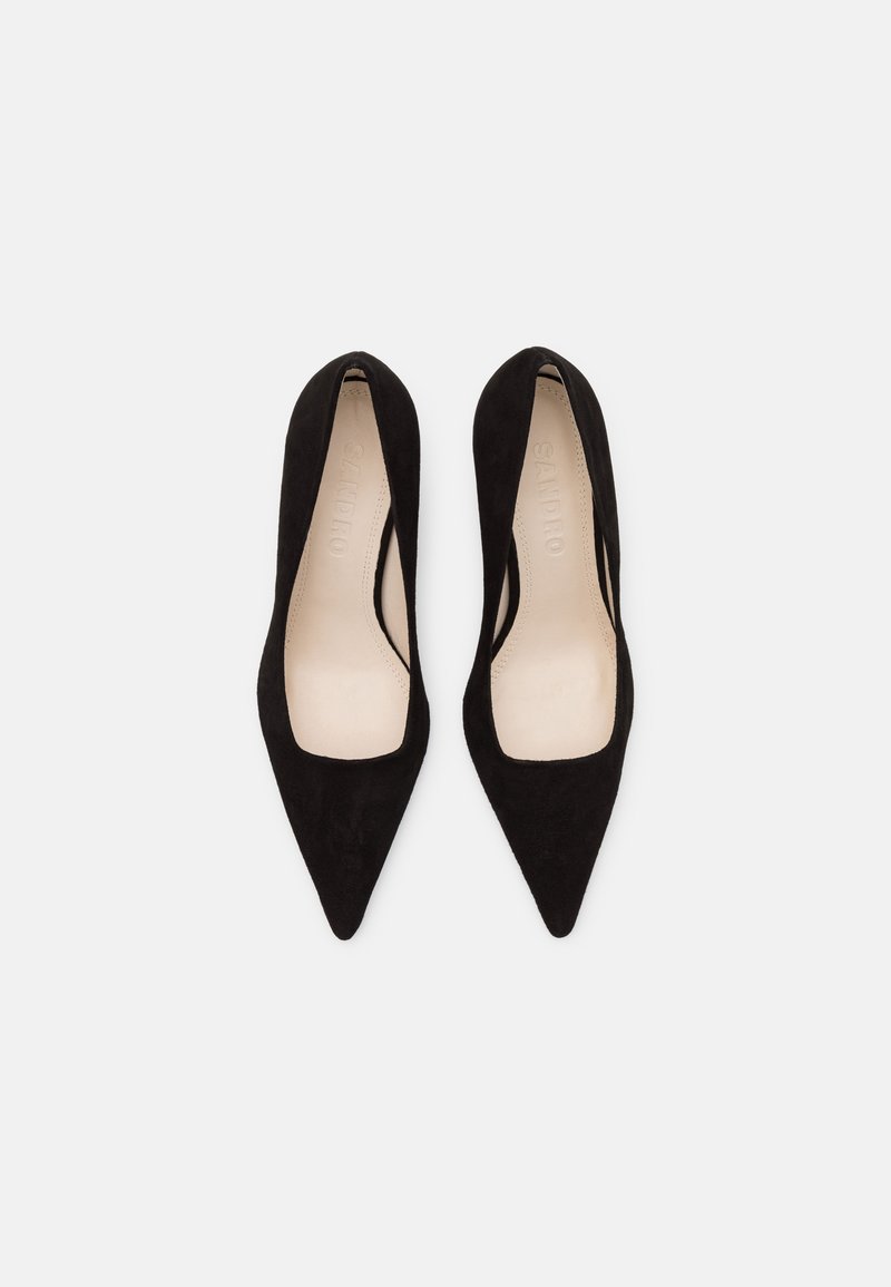 Scarpe nere in suede con tacco alto e punta affusolata, con un décolleté basso, presentano una fodera interna beige e una branding minimale sulla soletta.