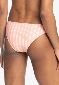 Ružové bikiny s bielymi vertikálnymi pruhmi, s hladkou textúrou a vyšším strihom na nohách, z pohľadu zozadu.
