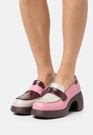 Scarpe con piattaforma multicolore con tomaia in pelle lucida marrone e rosa, accenti beige a contrasto e un design del tallone curvo e sovradimensionato.