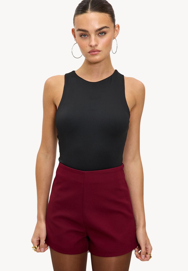 Body noir sans manches avec un col rond, associé à un short taille haute bordeaux, présentant une texture lisse et une coupe ajustée.