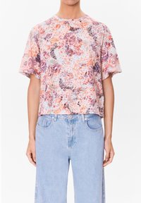 Halenka s krátkým rukávem s květinovým potiskem v kombinaci růžové, fialové a béžové barvy, vyrobená z lehkého materiálu s uvolněným střihem.