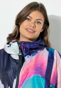 Bunte, leichte Jacke mit einem abstrakten Muster in den Farbtönen Lila, Pink und Blau. Das Material wirkt glatt mit einem glänzenden Finish.