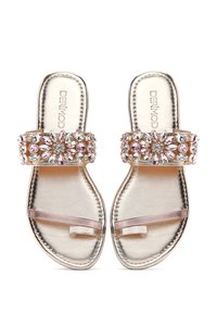 Sandali in oro con una ampia fascia decorata di cristalli che presenta pietre rosa e trasparenti; suola piatta con una sottile cinghia metallica.