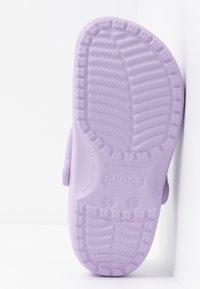 Semelle de sandale Crocs violet clair avec motif de bande de roulement texturé et marquages de taille pour hommes 4 et femmes 6 visibles sur fond blanc.