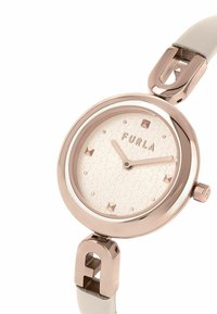 Montre Furla avec un boîtier rond en or rose, un bracelet en cuir blanc, un cadran à motif avec le logo de la marque et des accents de clous, ainsi que des aiguilles minimalistes.