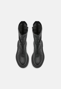 Stivaletti neri in pelle con superficie liscia, tacco basso, zip laterali e punte arrotondate. Presentano un design minimalista e una silhouette elegante.