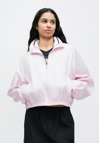 Ροζ cropped μπουφάν με ψηλό γιακά και ελαστικές μανσέτες, διαθέτει ολόκληρο φερμουάρ μπροστά και μαύρες λεπτομέρειες κατά μήκος του γιακά.