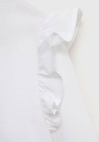 Detaliu al unei bluze albe cu manșete volan. Materialul pare neted, cu o ușoară strălucire. Marginile sunt curate, fără modele sau accente vizibile.