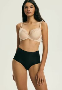 Beiger BH mit Spitzenverzierung und Bügel, kombiniert mit hoch tailliertem schwarzem Slip. Weicher, strukturierter Stoff; neutrale Töne; unterstützendes Design.
