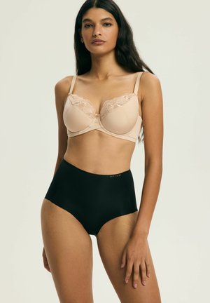 Beiger BH mit Spitzenverzierung und Bügel, kombiniert mit hoch tailliertem schwarzem Slip. Weicher, strukturierter Stoff; neutrale Töne; unterstützendes Design.