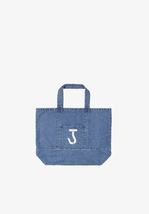 Blauwe denim draagtassen met dubbele hengsels en een voorvak met een witte gestileerde letter "J" applicatie.