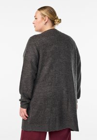 Veľká tmavošedá cardigan s rebrovanou textúrou, dlhými rukávmi a bočnými rozparkami, vyrobená z mäkkého pleteného materiálu.