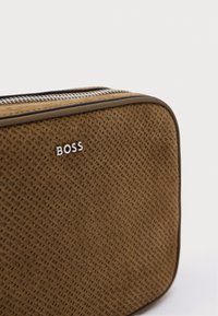 Καφέ τσάντα με υφή και φερμουάρ, διακοσμημένη με μεταλλικό λογότυπο "BOSS". Μαλακό υλικό με ξεχωριστό υφαντό σχέδιο.