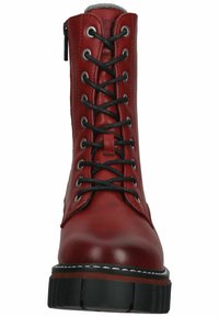 Bota de cuero rojo con cordones negros, un cuello acolchado y una suela gruesa negra. Presenta ojales plateados y una textura lisa.