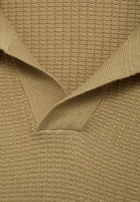 Tan knitted sweater with a v-neck design. Textured fabric featuring a ribbed pattern, showcasing overlapping collar details.