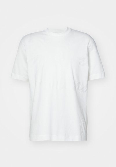 Camiseta blanca de manga corta hecha de algodón, con un clásico escote redondo y un corte holgado, sin logotipos ni patrones visibles.