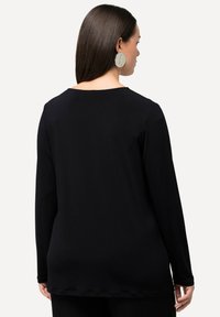 Schwarzes Langarmshirt mit rundem Ausschnitt, aus glattem Stoff, mit geradem Schnitt und feinen Nahtdetails am Saum.