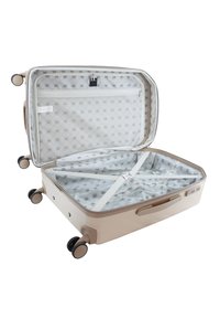 Beige hard-shell suitcase with four wheels, zip closure, and interior mesh pocket. Features cross straps and a patterned lining.