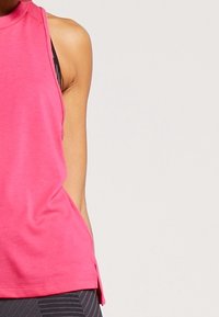 Ljusröd ärmlös topp med hög halsringning, med en avslappnad passform och sidoklipp för rörelsefrihet. Mjuk tygstruktur.