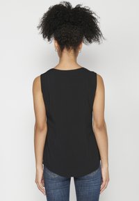 Top senza maniche nero con scollo rotondo, vestibilità comoda e orlo curvo. Tessuto liscio, senza motivi distintivi o accessori visibili.
