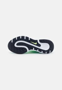 Semelle de chaussure de sport présentant une base en caoutchouc noir texturé, une semelle intermédiaire blanche et un accent vert avec un petit logo Nike lime.