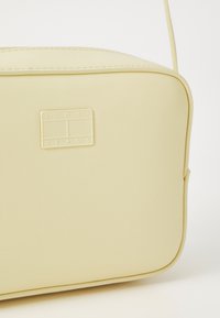 Żółta torebka crossbody z ekoskóry o prostokątnym kształcie, z fakturowaną powierzchnią i wypukłą metką z logo z przodu.