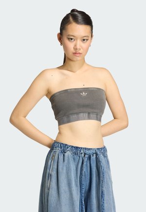 Szary prążkowany top typu tube z gładką, elastyczną opaską, ozdobiony małym logo, w połączeniu z luźnymi niebieskimi dżinsami z elastycznym pasem.