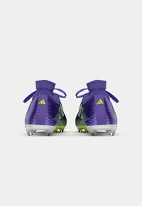 Ghete de fotbal purpurii cu un design texturat, accente verzi și suport pentru gleznă asemănător șosetelor. Cleme clare, ascuțite pe o talpă transparentă.