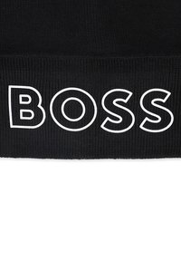 Bonnet en tricot noir avec une texture côtelée et un logo "BOSS" blanc bien en vue. Design simple et épuré.